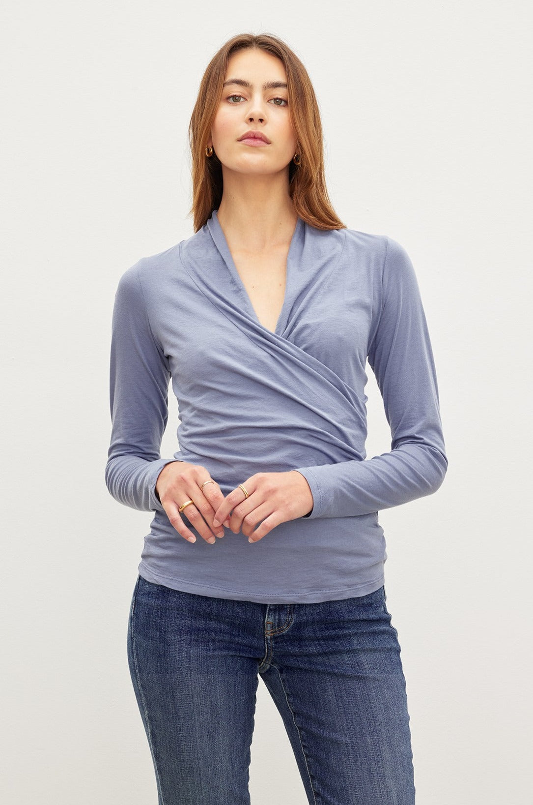 A woman wearing jeans and a Velvet by Graham & Spencer MERI WRAP FRONT FITTED TOP with clean lines.-36002799452353