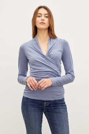 A woman wearing jeans and a Velvet by Graham & Spencer MERI WRAP FRONT FITTED TOP with clean lines.