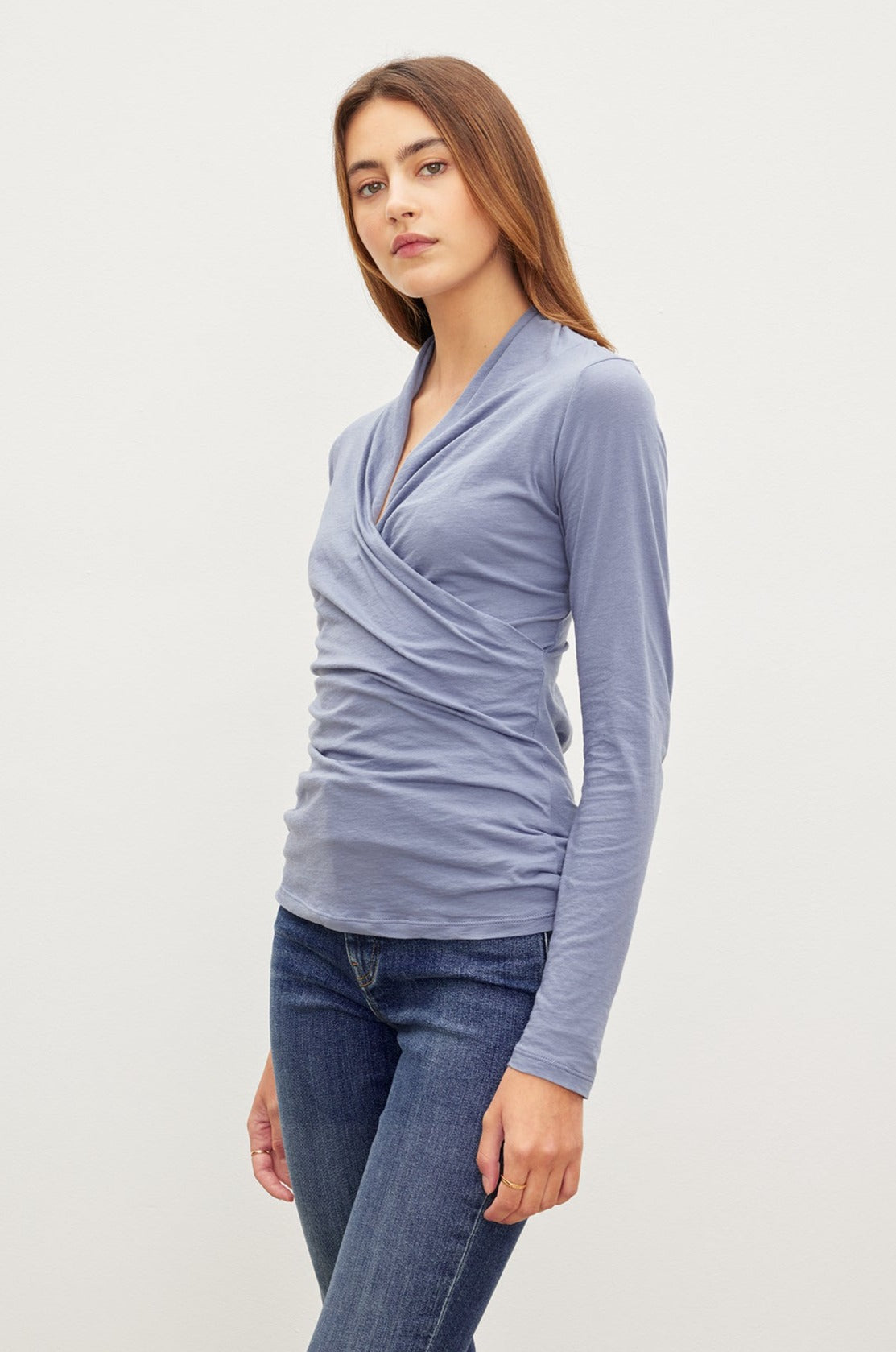   A woman wearing jeans and the Velvet by Graham & Spencer MERI WRAP FRONT FITTED TOP with clean lines. 