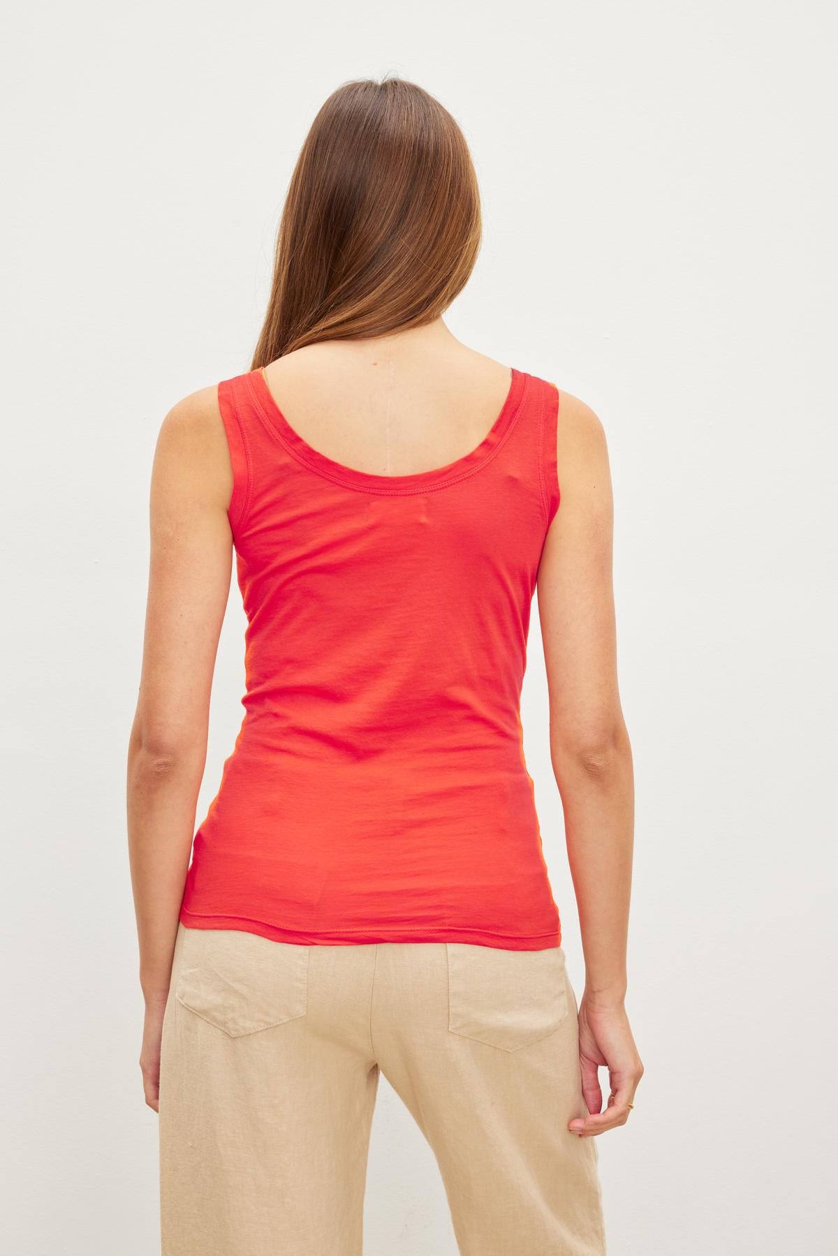   A woman wearing a MOSSY GAUZY WHISPER FITTED TANK by Velvet by Graham & Spencer, embracing the back to basics fashion trend with her tan pants. 