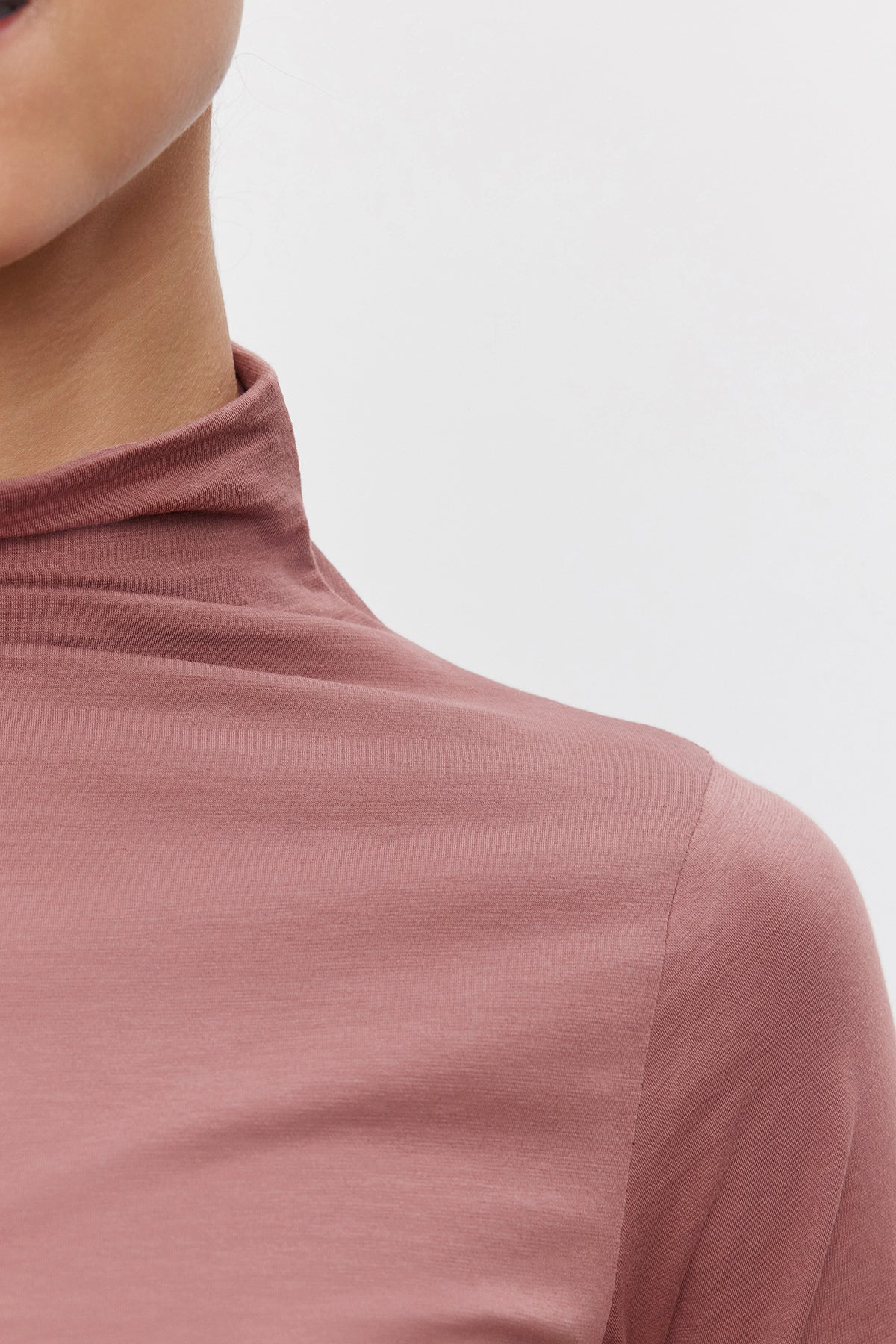   Close-up of a person wearing the TALISIA TEE in light pink by Velvet by Graham & Spencer. Only the lower half of the face, neck, and upper torso are visible against a plain white background, showcasing this versatile wardrobe essential. 