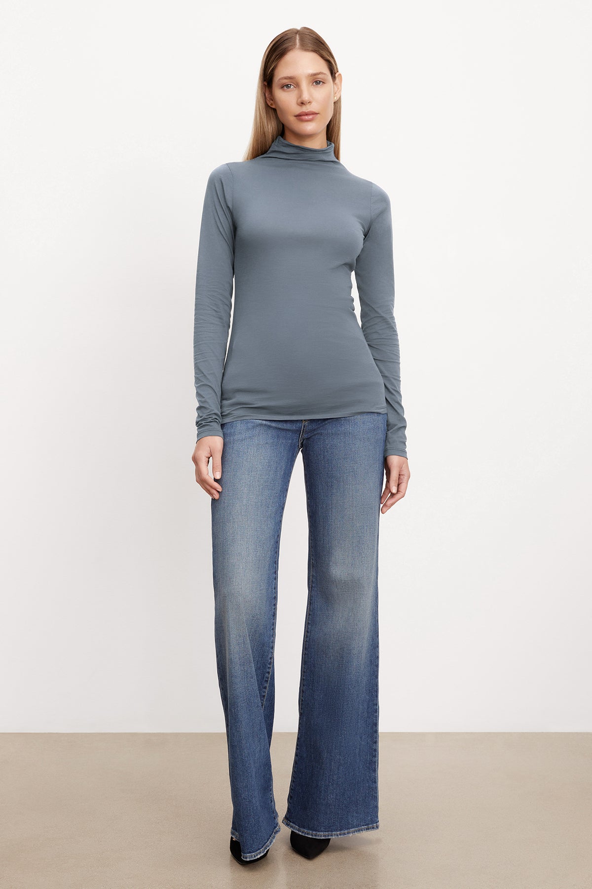   A model wearing a TALISIA GAUZY WHISPER FITTED MOCK NECK TEE from Velvet by Graham & Spencer and wide leg jeans. 