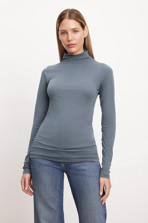 A woman wearing a Velvet by Graham & Spencer TALISIA GAUZY WHISPER FITTED MOCK NECK TEE and jeans.
