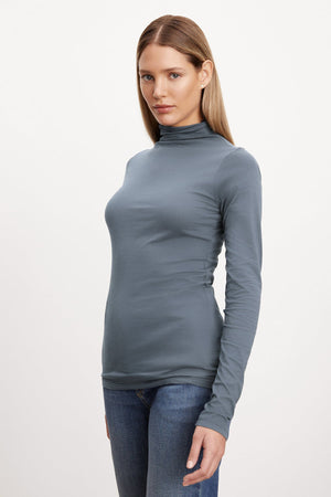 A versatile wardrobe staple, the woman is wearing a TALISIA GAUZY WHISPER FITTED MOCK NECK TEE by Velvet by Graham & Spencer.