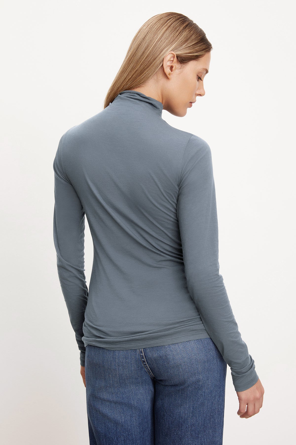   The back view of a woman wearing a TALISIA GAUZY WHISPER FITTED MOCK NECK TEE by Velvet by Graham & Spencer is a versatile wardrobe staple in the fashion world. 