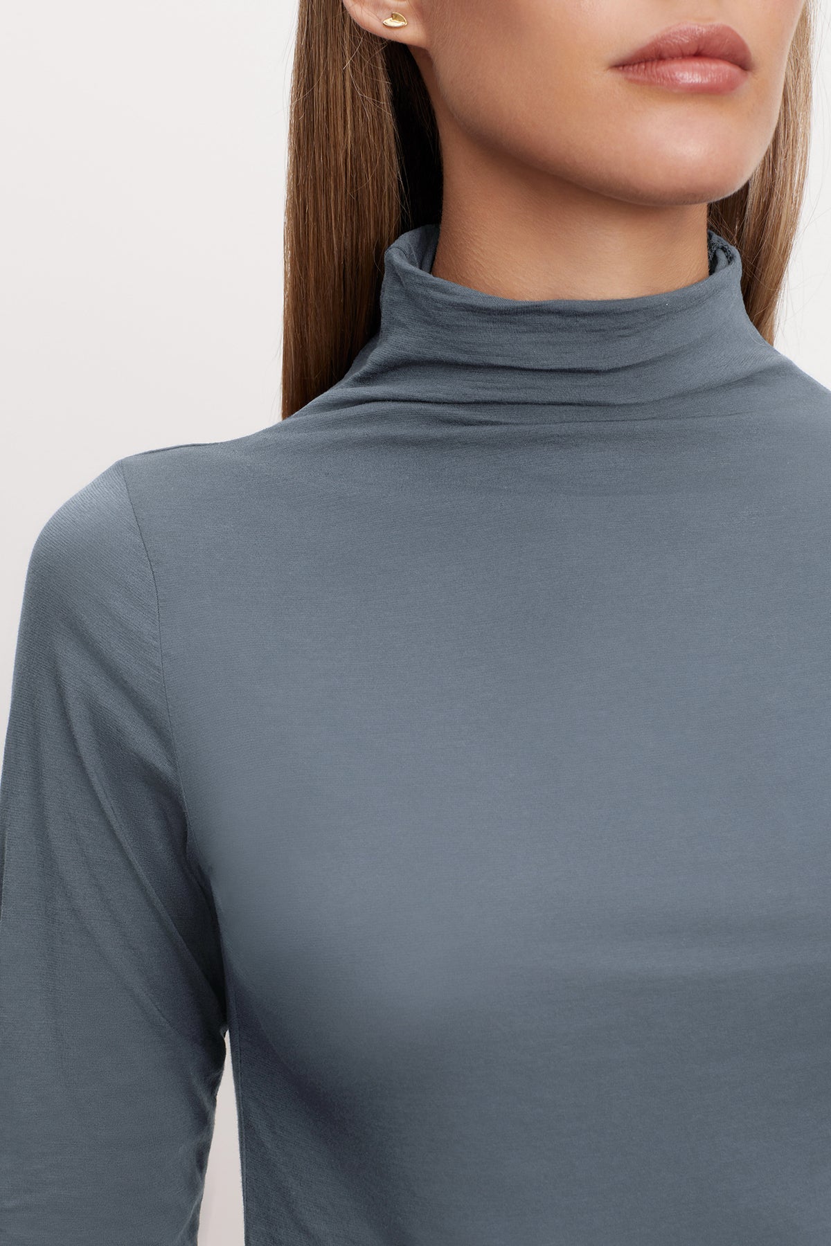   A woman wearing a grey TALISIA GAUZY WHISPER FITTED MOCK NECK TEE, a versatile wardrobe staple in the fashion world by Velvet by Graham & Spencer. 