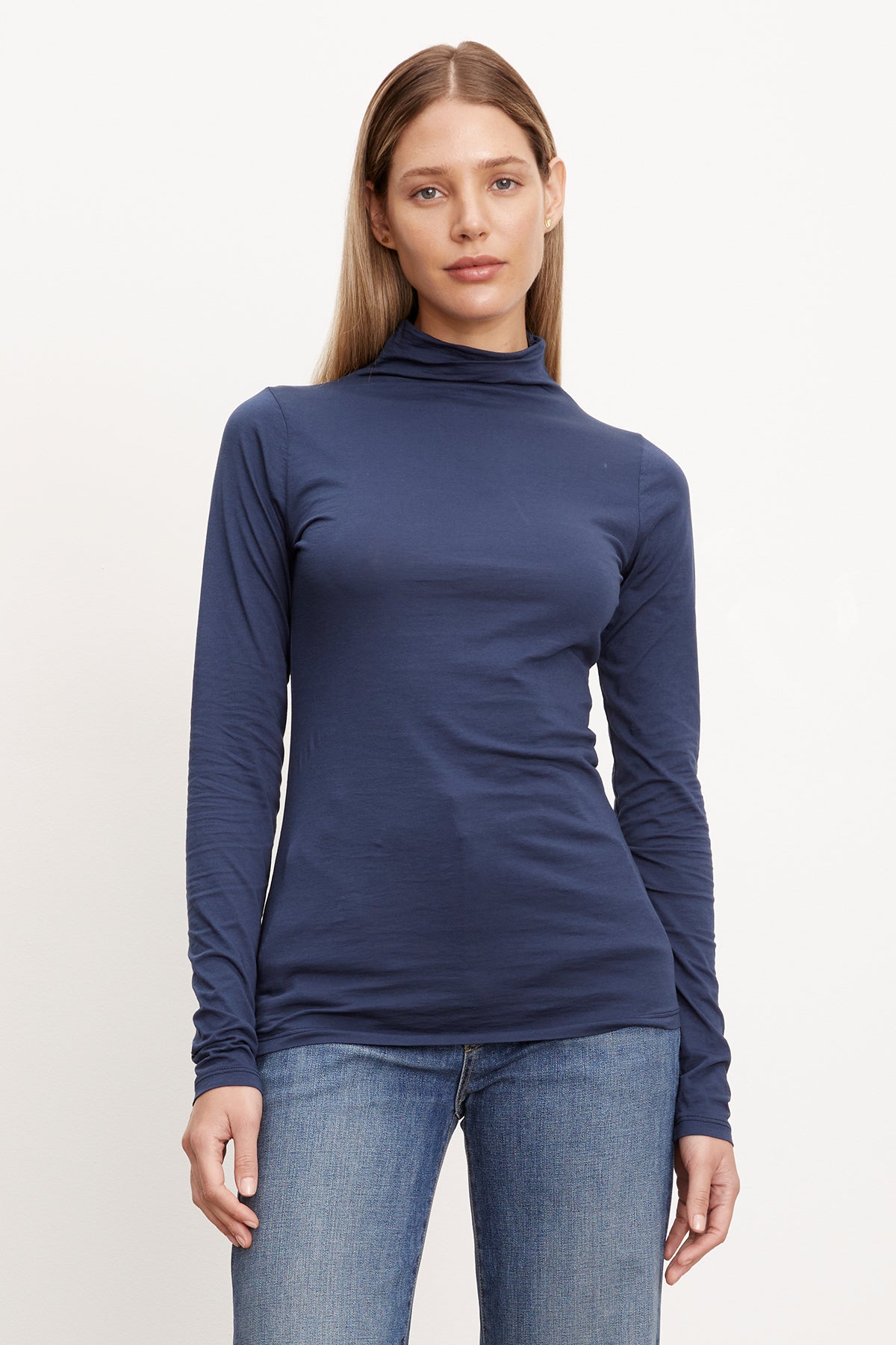   A woman in a Velvet by Graham & Spencer TALISIA GAUZY WHISPER FITTED MOCK NECK TEE effortlessly showcases a fashionable and timeless look. 