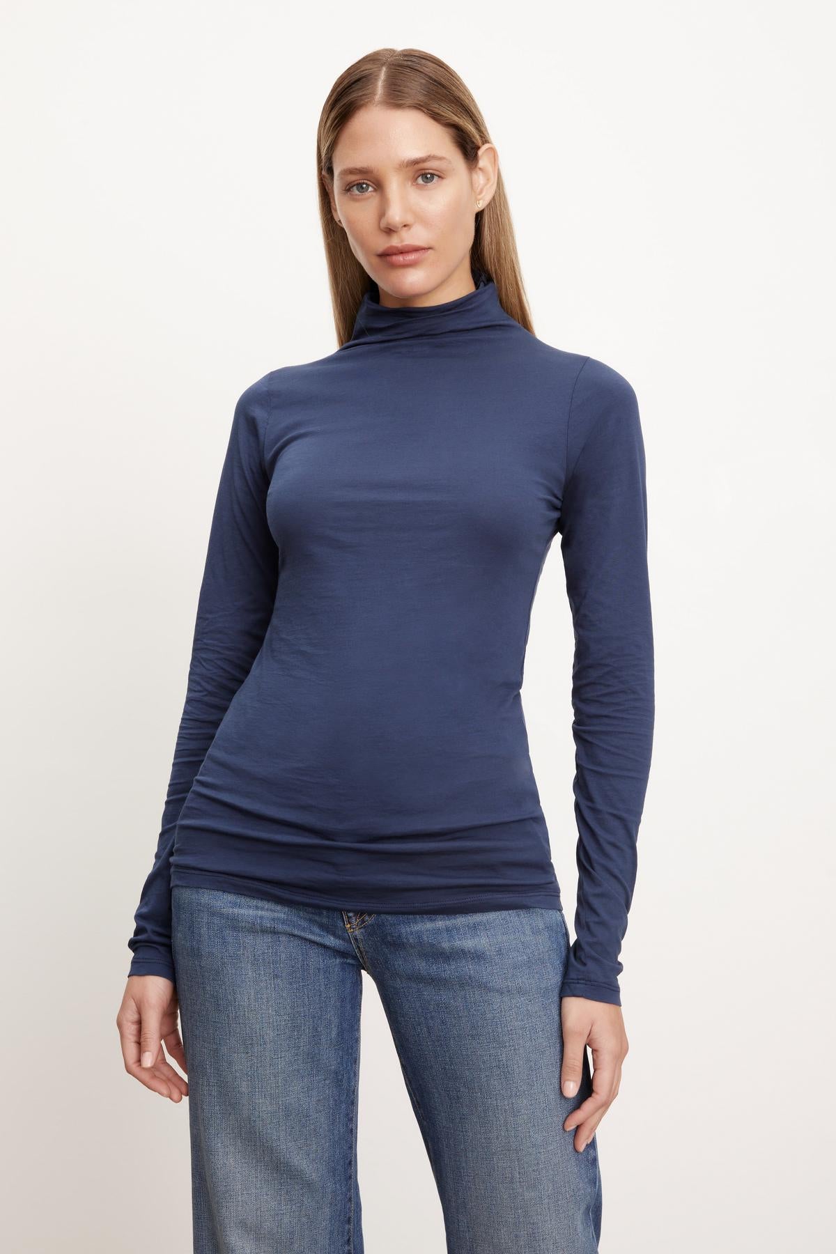 A woman showcasing a fashion-forward TALISIA GAUZY WHISPER FITTED MOCK NECK TEE by Velvet by Graham & Spencer, paired effortlessly with comfortable jeans - a perfect wardrobe staple.-26895431729345