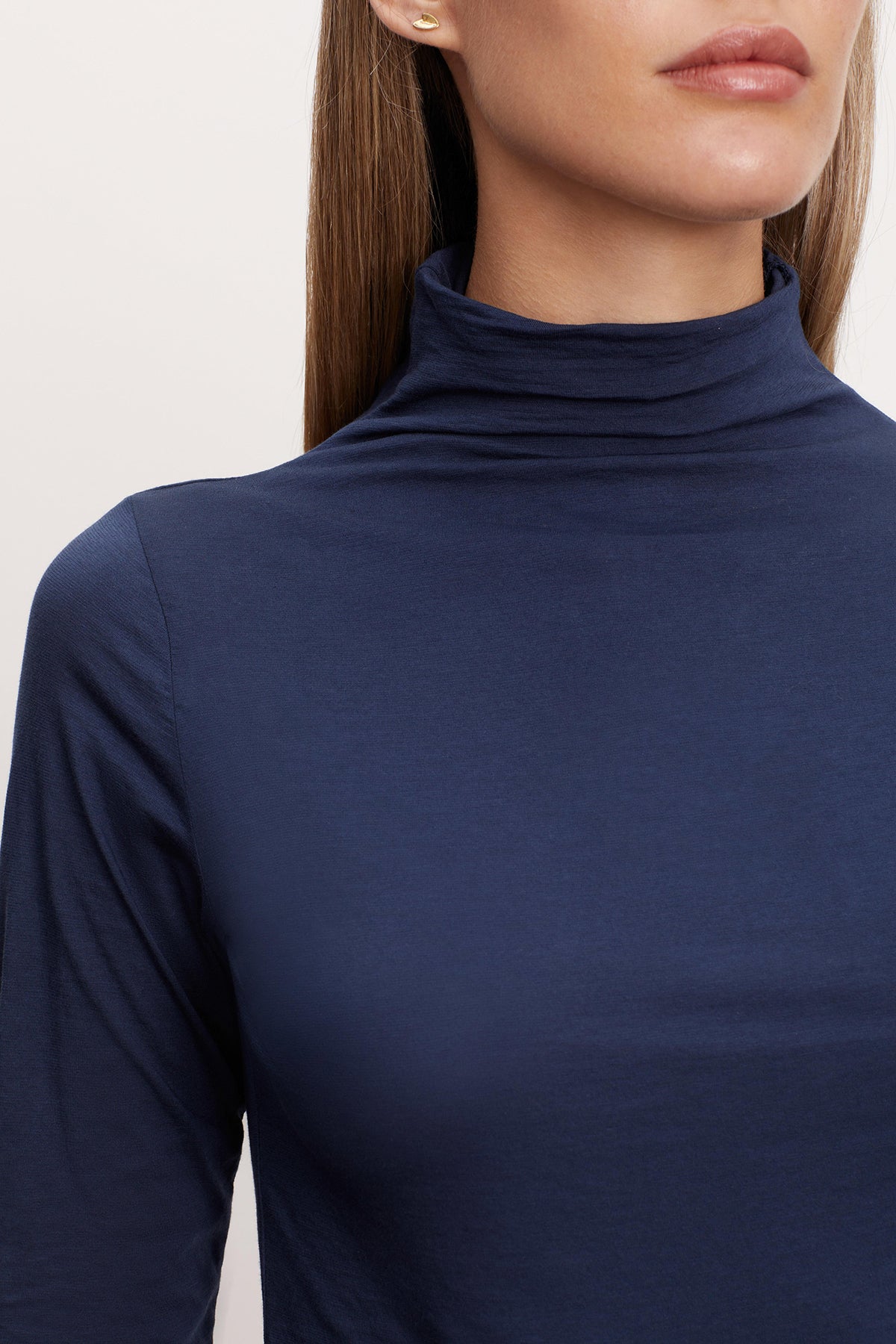 A woman wearing a fashionable Velvet by Graham & Spencer navy Talisia Gauzy Whisper Fitted Mock Neck Tee, a versatile wardrobe staple.-26895433793729