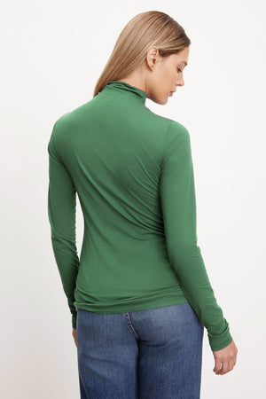 The back view of a woman wearing a Velvet by Graham & Spencer TALISIA GAUZY WHISPER FITTED MOCK NECK TEE, a wardrobe staple in the fashion world.