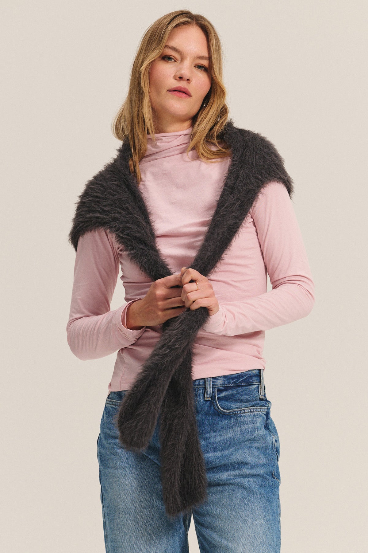 Wearing the TALISIA TEE by Velvet by Graham & Spencer in light pink, paired with blue jeans and a dark gray faux fur scarf, this look stands out as a true wardrobe staple against a plain background.