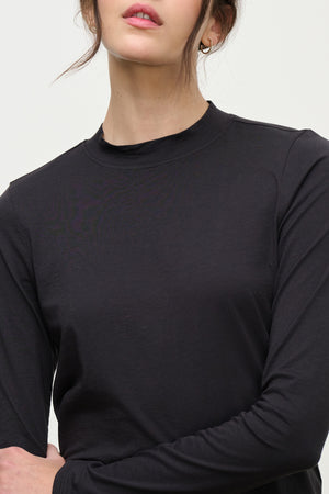 A model wears the TRISH TEE by Velvet by Graham & Spencer—a black long-sleeve, crew neck top—shown from shoulders to lips against a plain background, ideal for everyday wear.