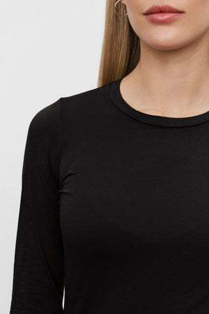 A person with long hair is wearing a black ZOFINA TEE by Velvet by Graham & Spencer. Their face is partially visible.