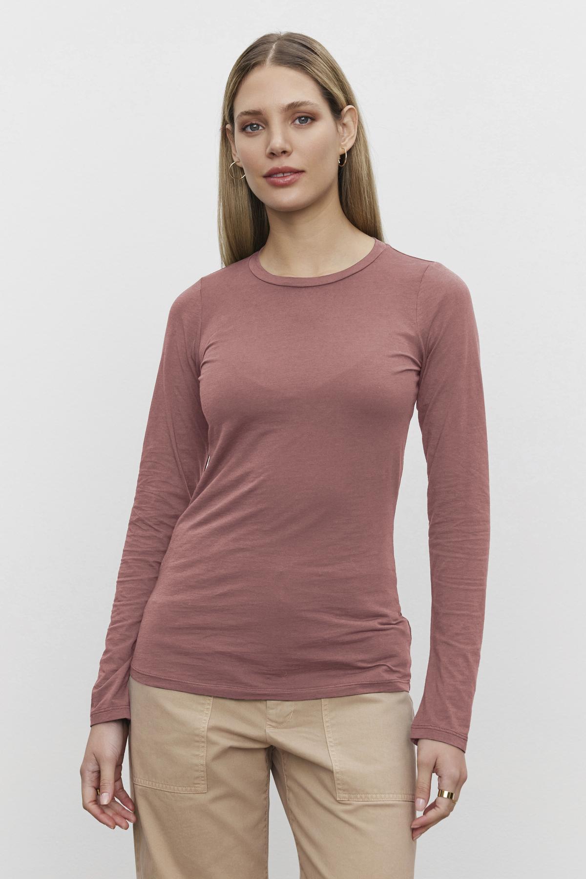   A woman with long blonde hair is wearing the ZOFINA TEE in ultra-soft gauzy whisper fabrication by Velvet by Graham & Spencer, paired with beige pants, against a plain white background. 