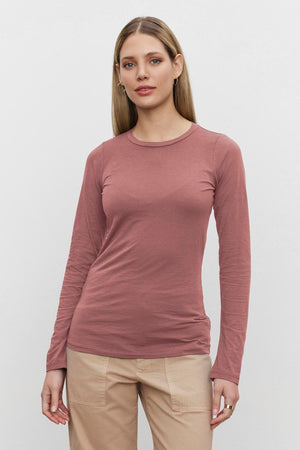 A woman with long blonde hair is wearing the ZOFINA TEE in ultra-soft gauzy whisper fabrication by Velvet by Graham & Spencer, paired with beige pants, against a plain white background.