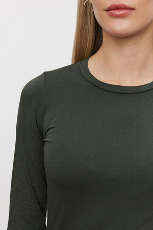 A woman wearing a ZOFINA TEE by Velvet by Graham & Spencer in ultra-soft gauzy whisper dark green, with her face partially out of the frame. She has straight, long hair and is wearing a hoop earring.