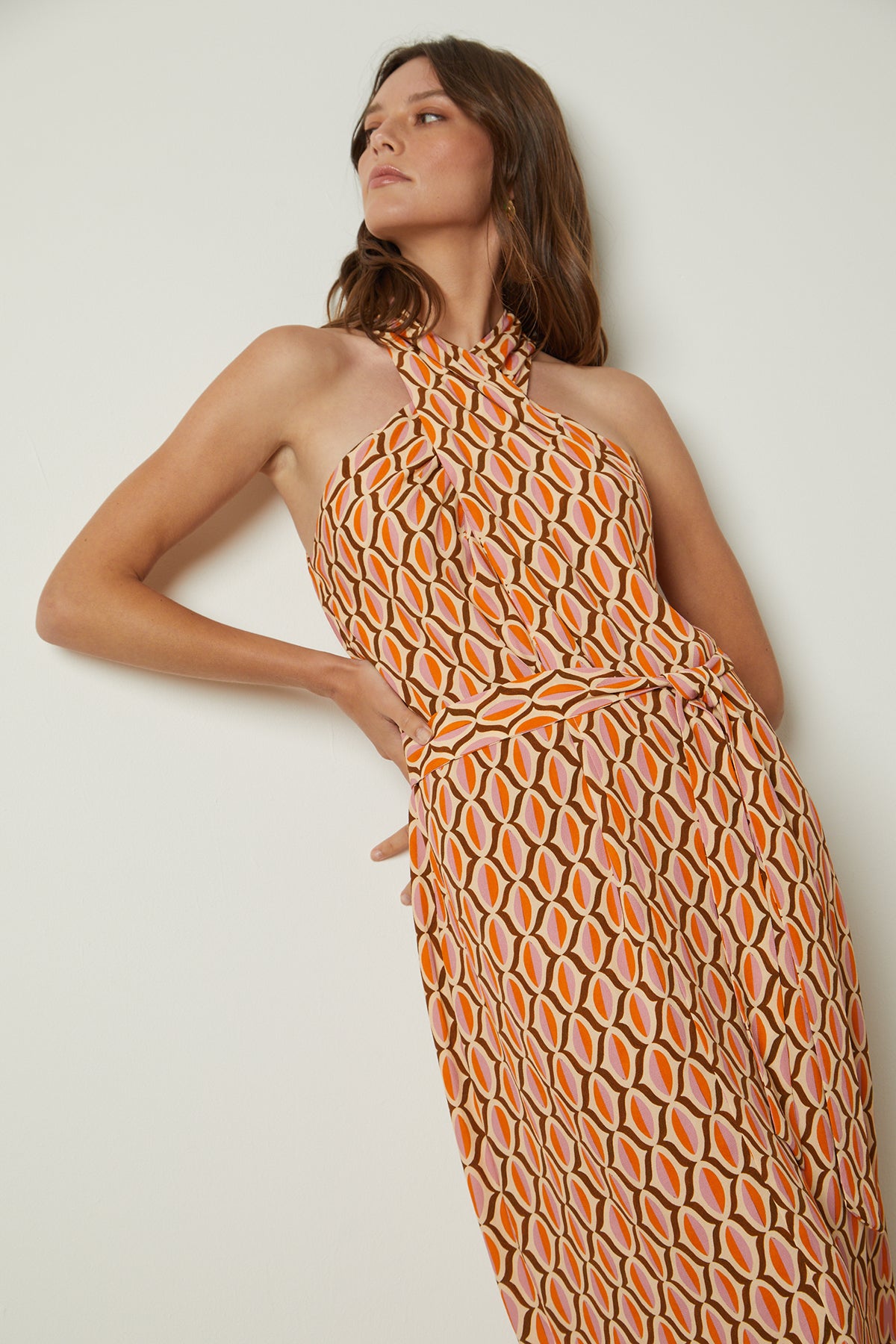   a woman wearing the CATERINA PRINTED DRESS by Velvet by Graham & Spencer which is an orange and white geometric print dress. 