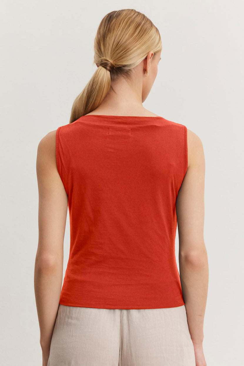 A person with blond hair tied in a low ponytail is shown from the back, wearing a Velvet by Graham & Spencer EMILIA TANK TOP and beige pants.