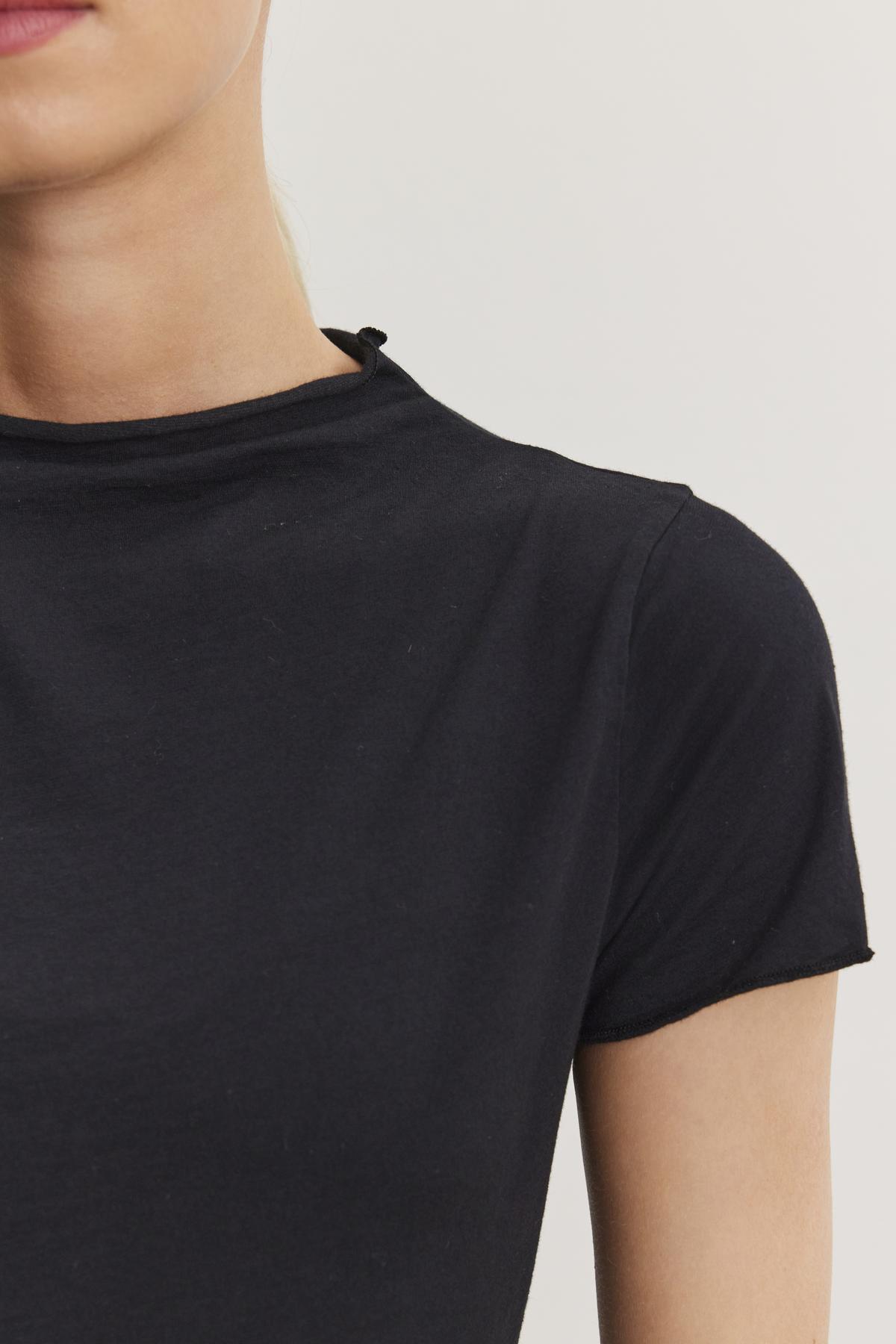 Close-up of a person wearing a fitted cropped silhouette black JACKIE MOCK NECK TEE by Velvet by Graham & Spencer. The photo shows the upper torso and partial face against a plain white background.-37104257892545