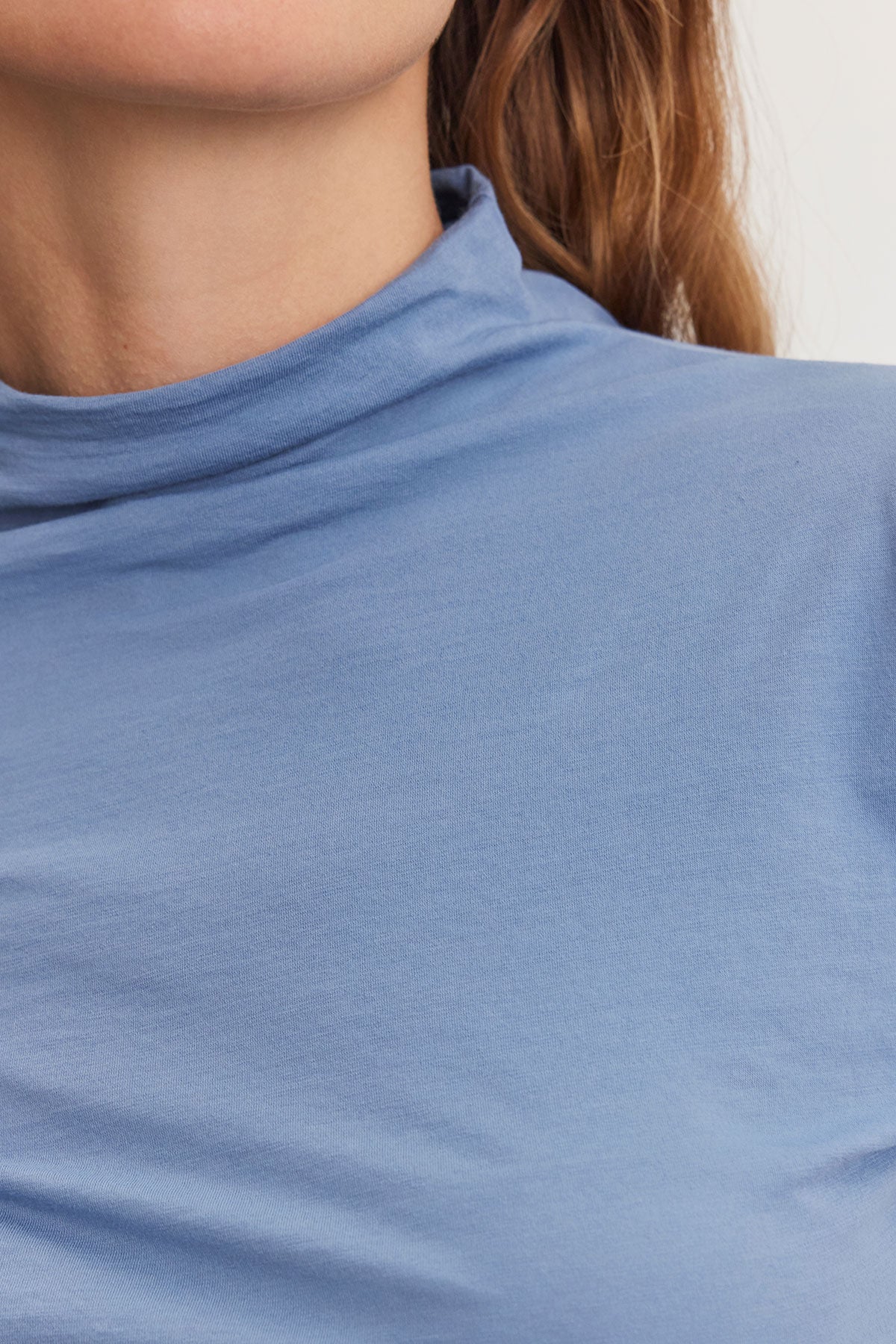   Close-up of a person wearing the TALISIA TEE by Velvet by Graham & Spencer, highlighting the versatility of this fashion wardrobe staple, with part of their hair visible on the right side. 