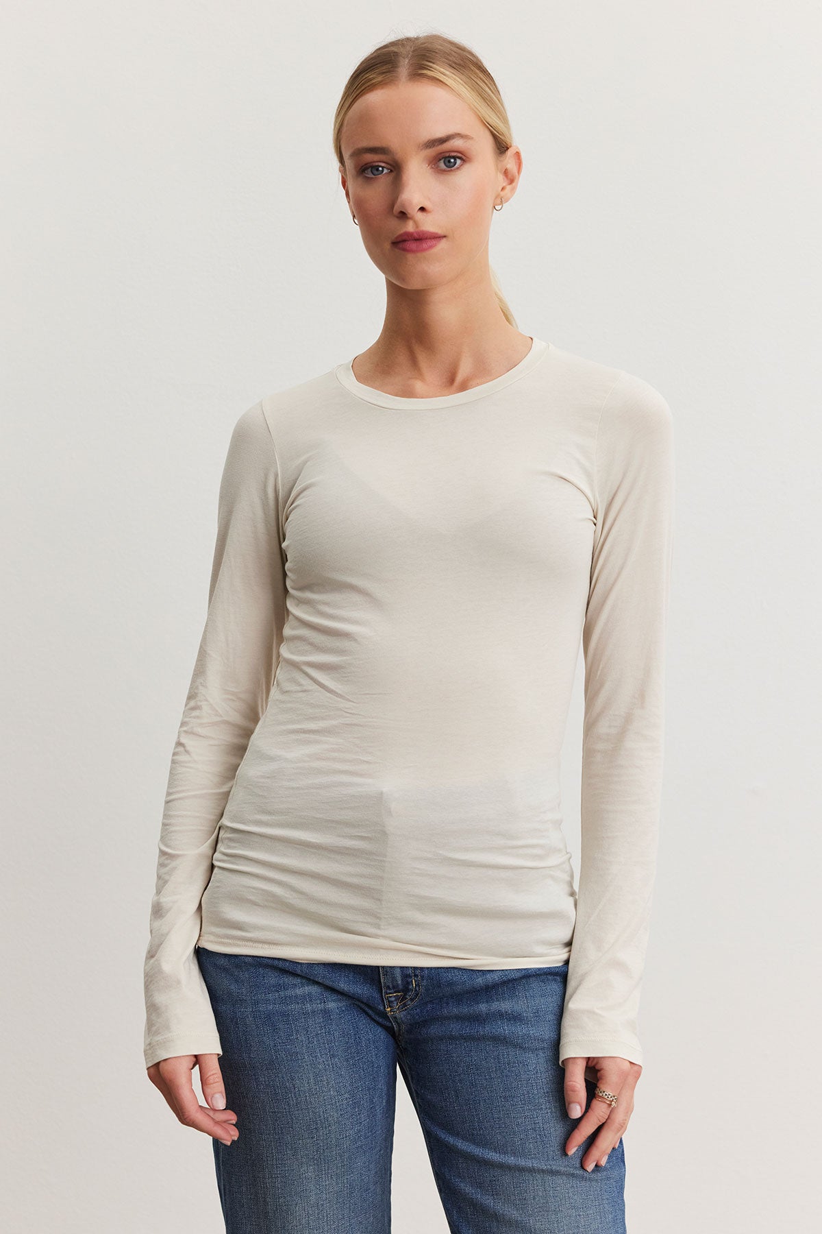   An individual wearing the ZOFINA TEE from Velvet by Graham & Spencer and blue jeans stands against a plain background. 