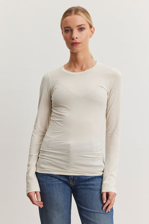 An individual wearing the ZOFINA TEE from Velvet by Graham & Spencer and blue jeans stands against a plain background.