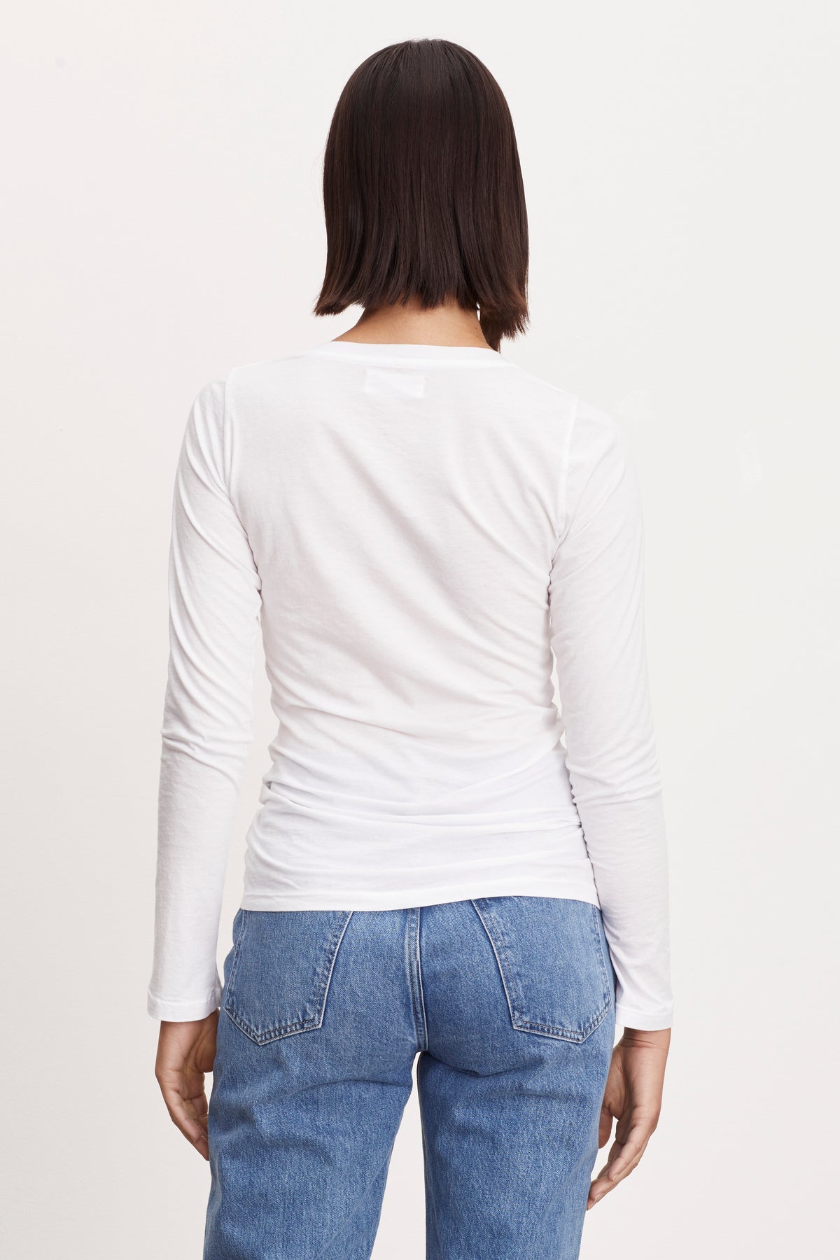  The back view of a woman wearing ZOFINA GAUZY WHISPER FITTED CREW NECK TEE by Velvet by Graham & Spencer jeans and a white t - shirt. 