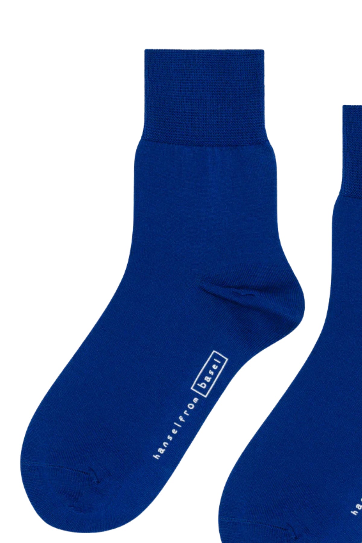   The TROUSER CREW SOCKS BY HANSEL FROM BASEL, in blue with a plain white background, are made from luxurious mercerized cotton and feature a ribbed cuff and white logo text near the toes. These socks by Hansel From Basel add comfort and style to any outfit. 