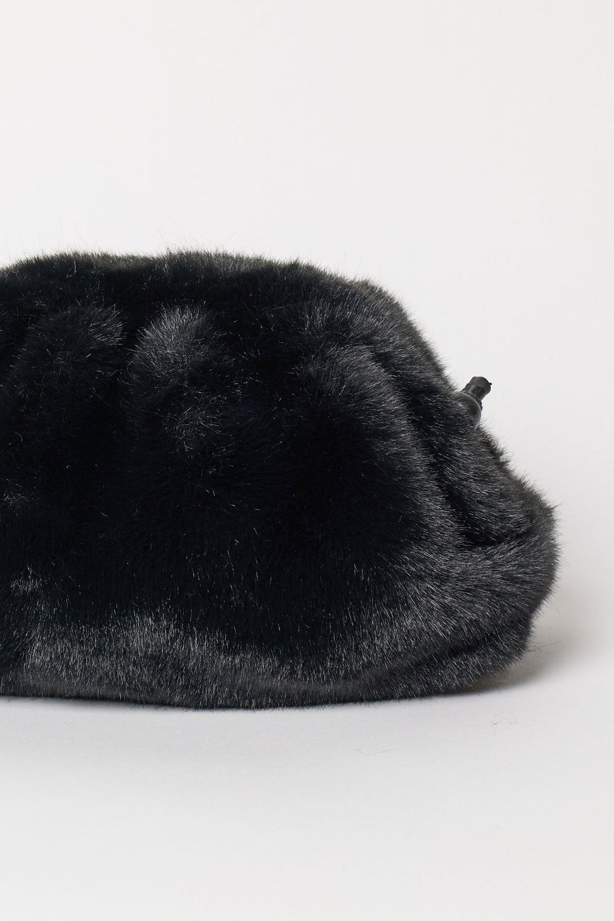 A close-up of the FAUX FUR CLUTCH by Velvet by Graham & Spencer, featuring black faux fur and a black drawstring closure, displayed against a plain white background.