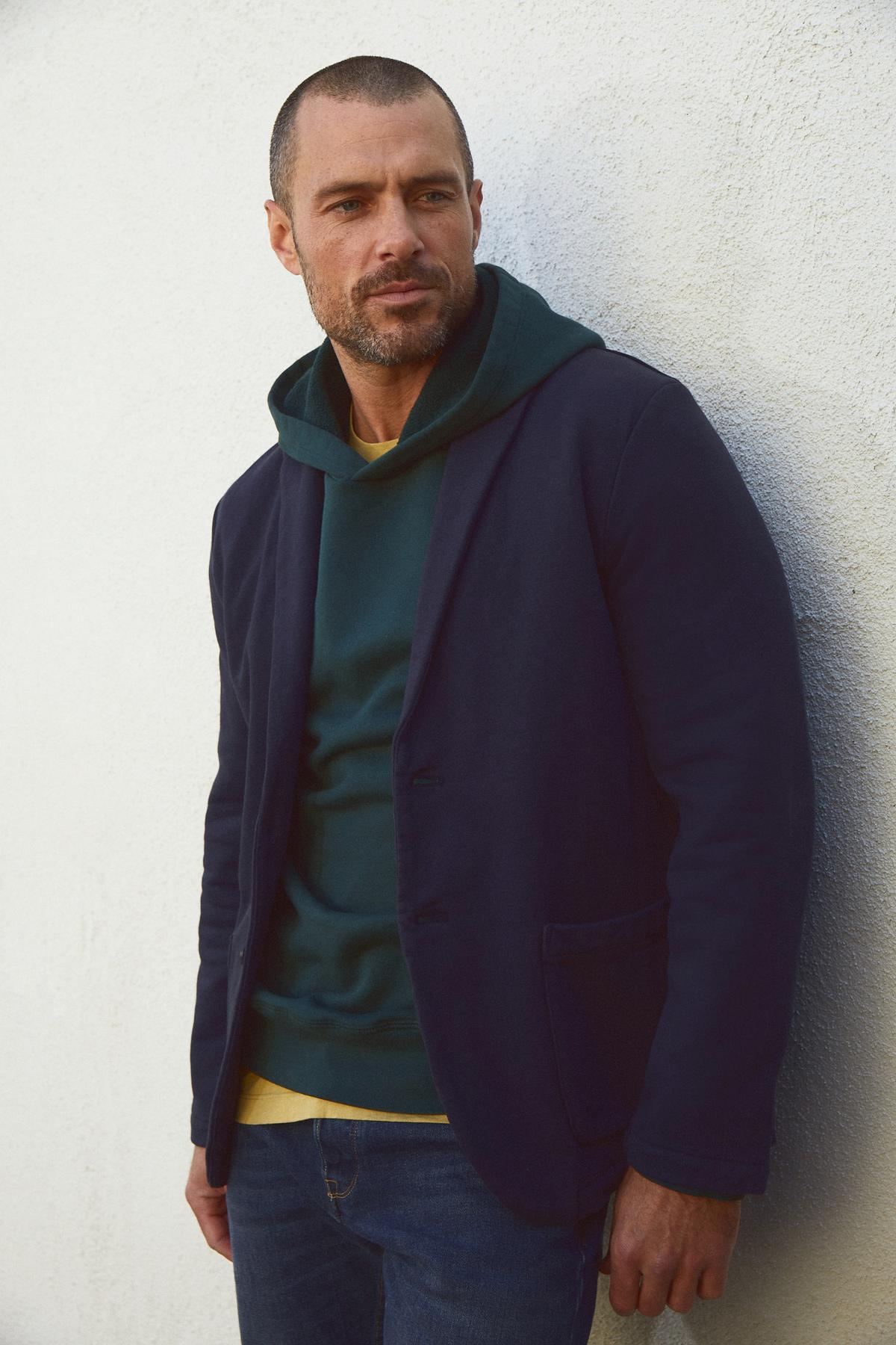   A man enjoying superior comfort in a cozy Velvet by Graham & Spencer Hopkin Pullover Hoodie and green hoodie. 