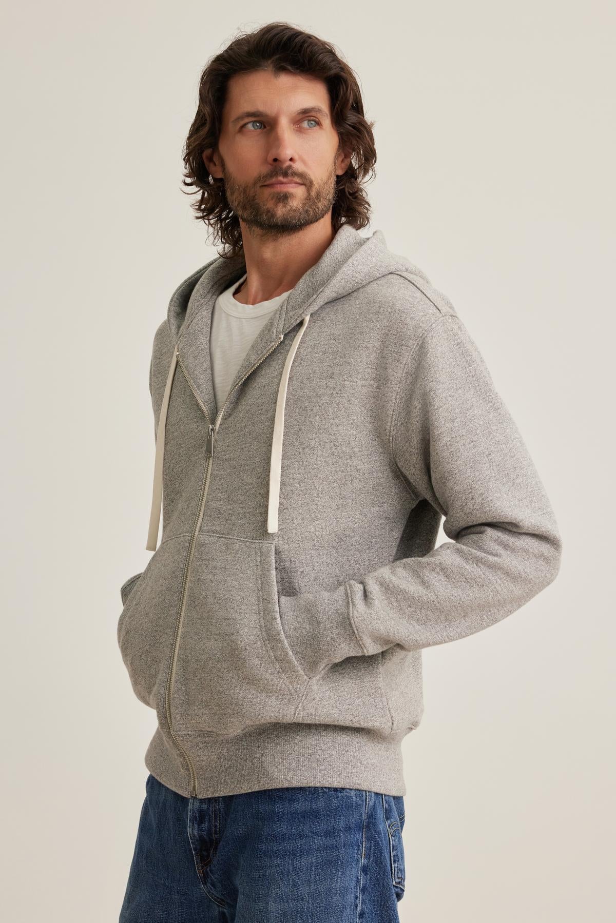   A person in a Velvet by Graham & Spencer DRACO HOODIE and jeans stands with hands in pockets against a plain background. 