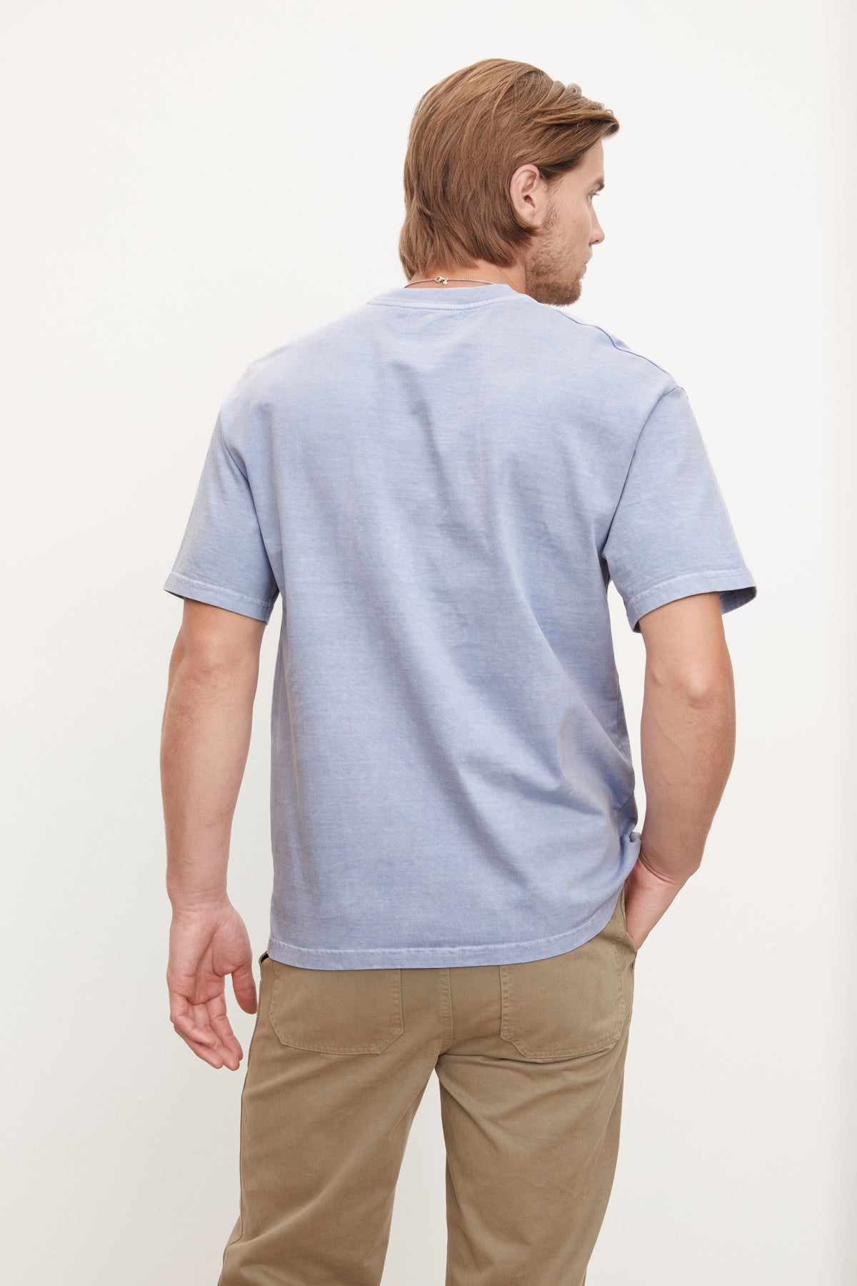   Man standing in profile view wearing a Velvet by Graham & Spencer Jacobi Heavy Jersey Crew Neck Tee in blue and tan pants. 