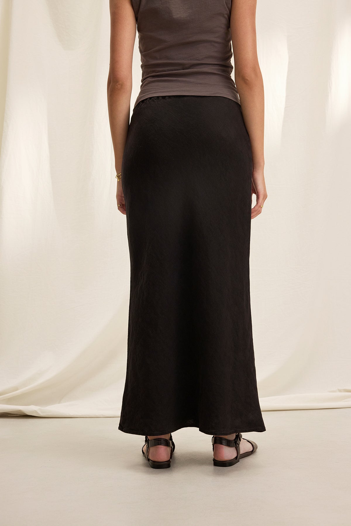 A person in a dark sleeveless top and the BEKA HEAVY LINEN SKIRT by Velvet by Graham & Spencer stands facing away against a light background.-38662914212033