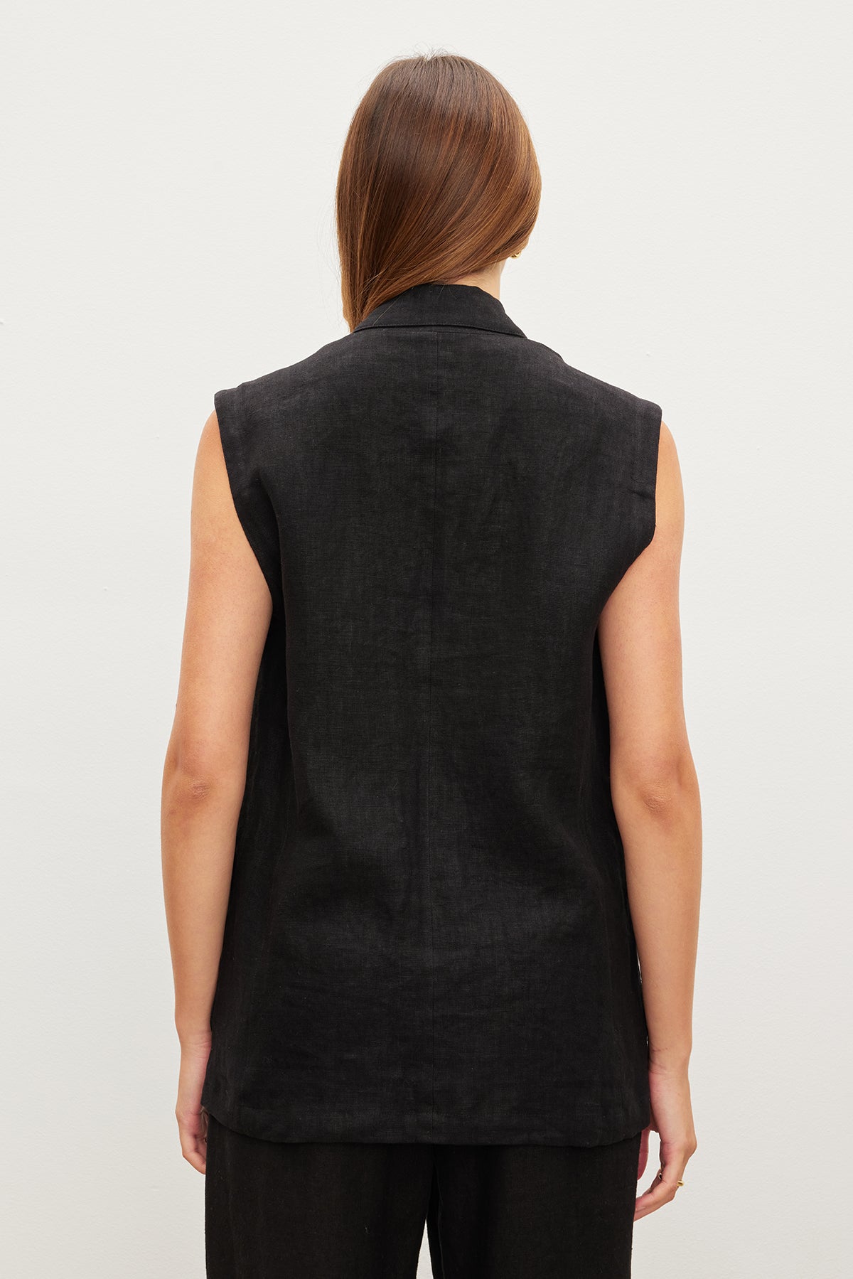 The back view of a woman wearing an oversized Velvet by Graham & Spencer BETHAN HEAVY LINEN SLEEVELESS BLAZER.-35982575403201