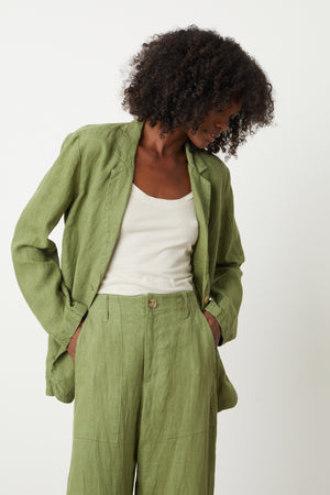 A woman wearing a green Velvet by Graham & Spencer CASSIE HEAVY LINEN BLAZER and pants.