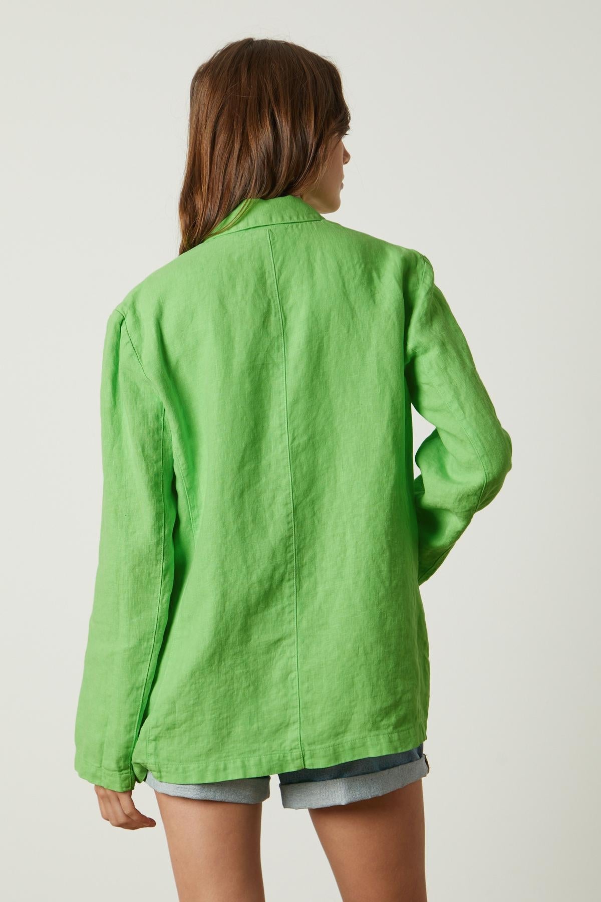 The back view of a woman wearing a Velvet by Graham & Spencer CASSIE HEAVY LINEN BLAZER.-26806262366401