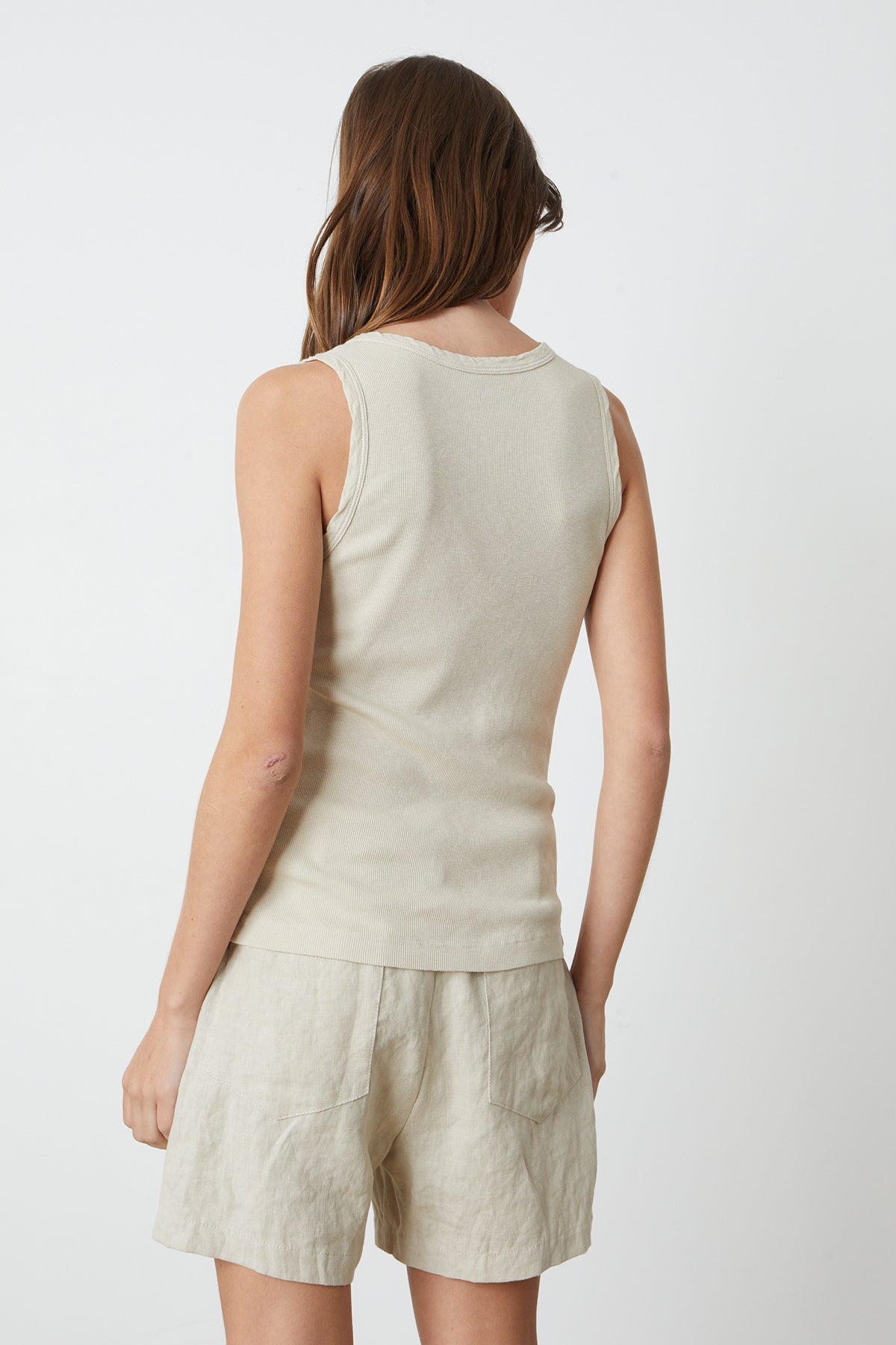   The back view of a woman wearing a Velvet by Graham & Spencer MAXIE RIBBED TANK TOP and shorts. 