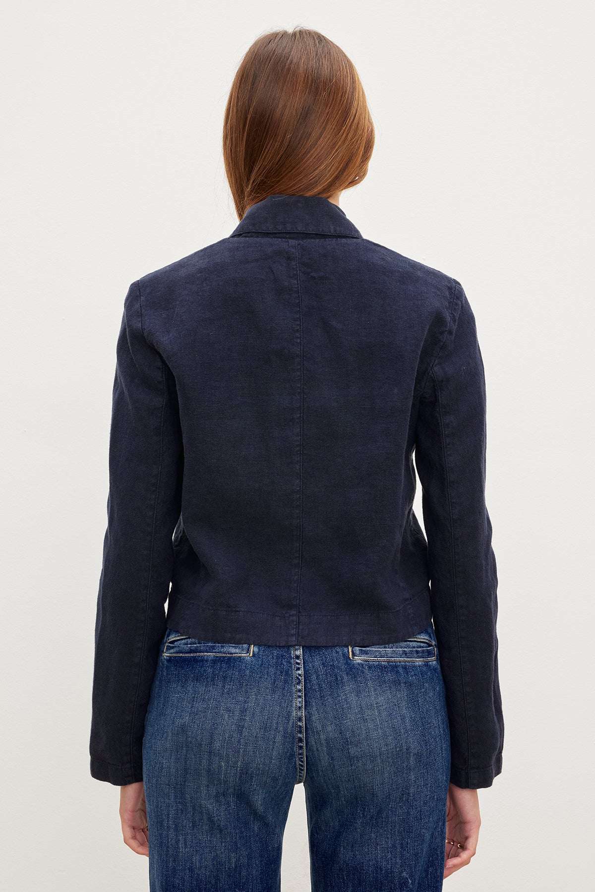   The back view of a woman wearing FINLEY HEAVY LINEN CROPPED BLAZER by Velvet by Graham & Spencer jeans and a blue jacket. 