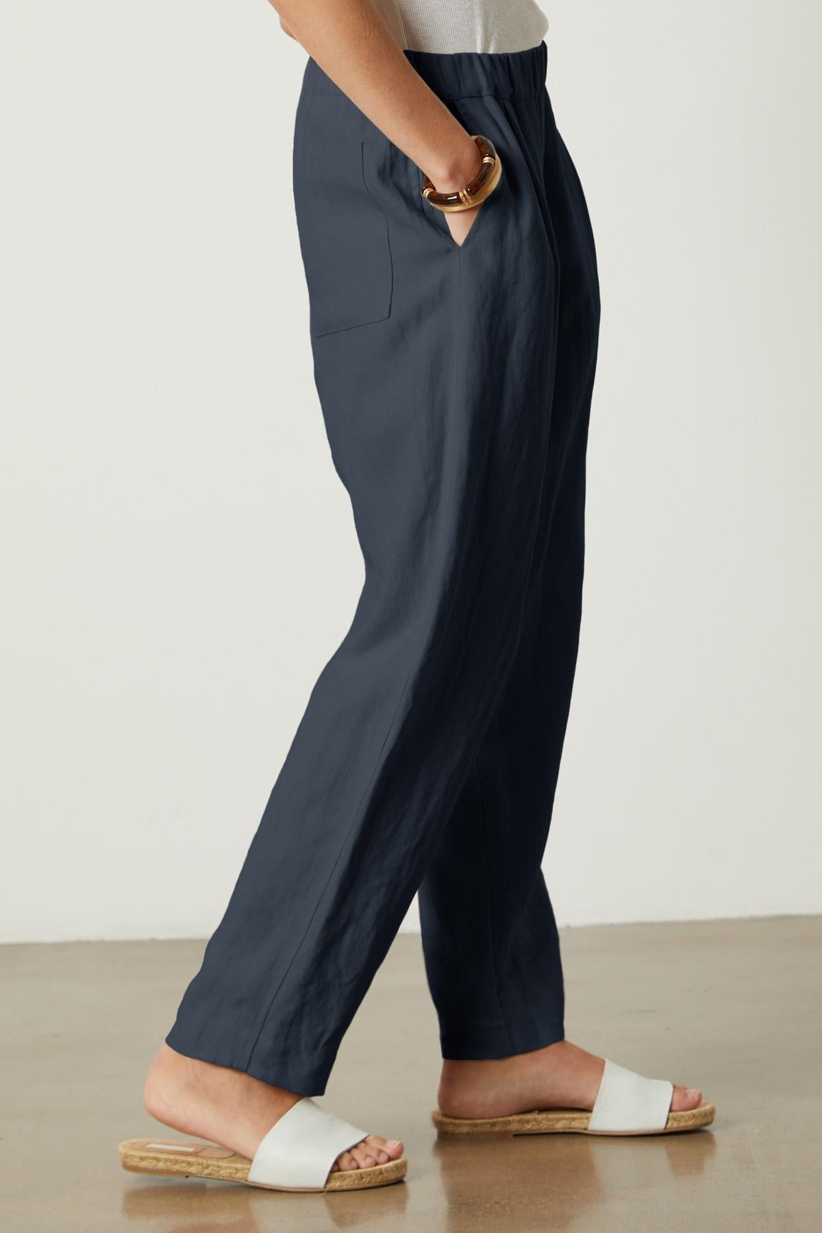   A woman wearing Velvet by Graham & Spencer navy linen trousers, with an elastic waist and rear patch pockets. 