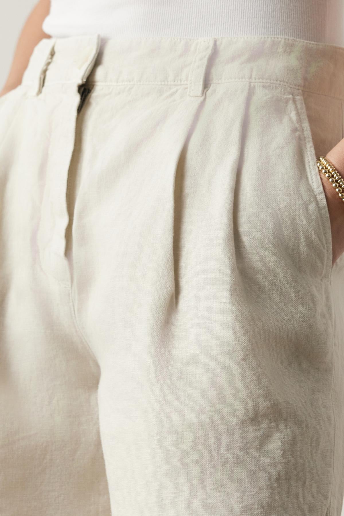 Close-up of a person wearing Velvet by Jenny Graham's LARCHMONT HEAVY LINEN SHORTS and a white top, focusing on the fabric texture and pocket detail.-36890975830209