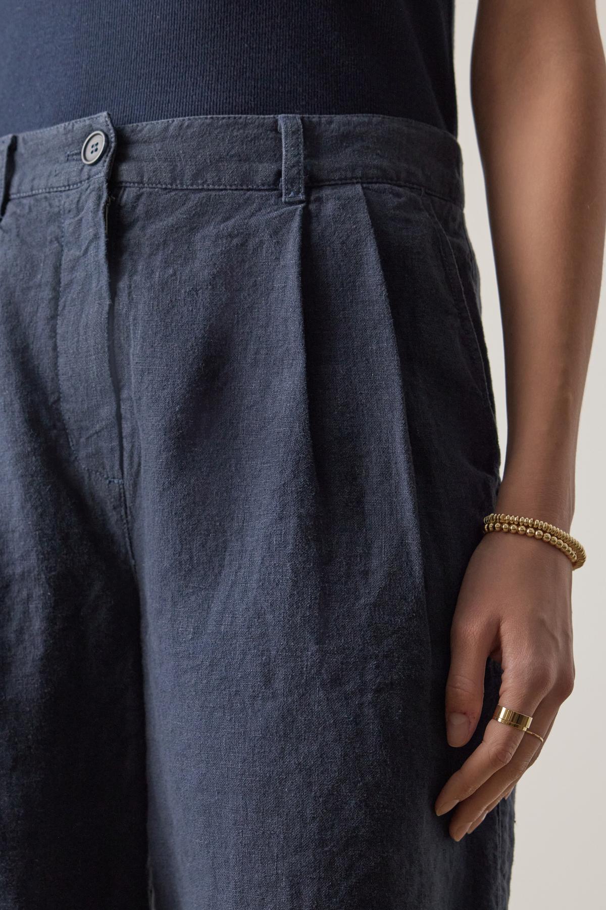   Close-up of a person wearing Velvet by Jenny Graham's LARCHMONT HEAVY LINEN SHORT with a hand resting on the hip, showcasing a golden bracelet and ring. 