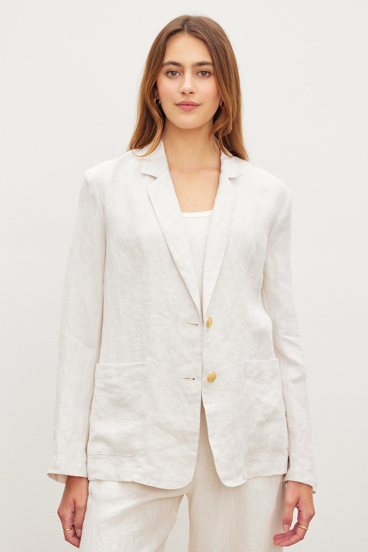   A woman wearing a white LENNY HEAVY LINEN BLAZER and pants by Velvet by Graham & Spencer. 