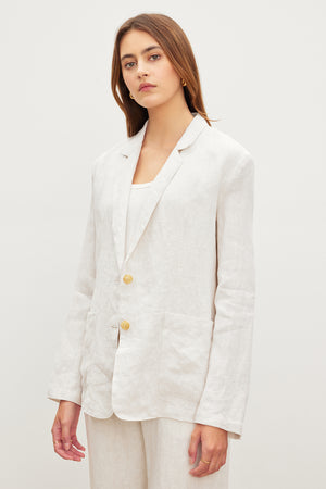 The model is wearing a white LENNY HEAVY LINEN BLAZER and pants by Velvet by Graham & Spencer.