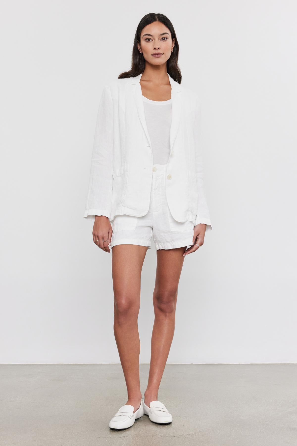   Woman in a Velvet by Graham & Spencer LENNY HEAVY LINEN BLAZER and shorts set with a white top, standing against a plain background, wearing white loafers. 