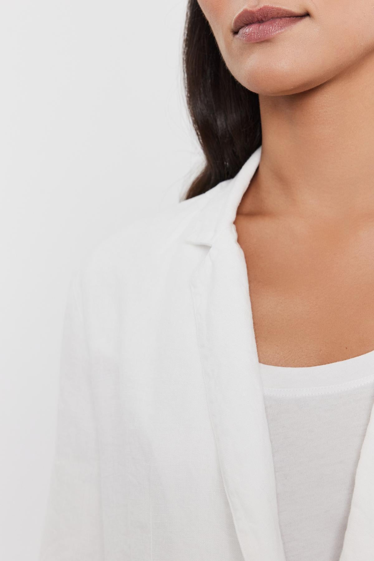   Close-up of a woman wearing a Velvet by Graham & Spencer LENNY HEAVY LINEN BLAZER over a white t-shirt, focusing on her lower face and neckline. 