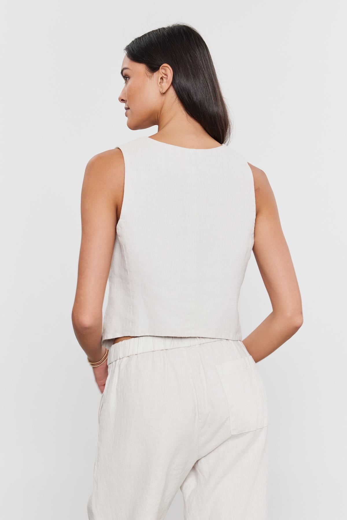   Rear view of a woman in a Velvet by Graham & Spencer MYLIE HEAVY LINEN VEST and pants, standing against a plain white background. 