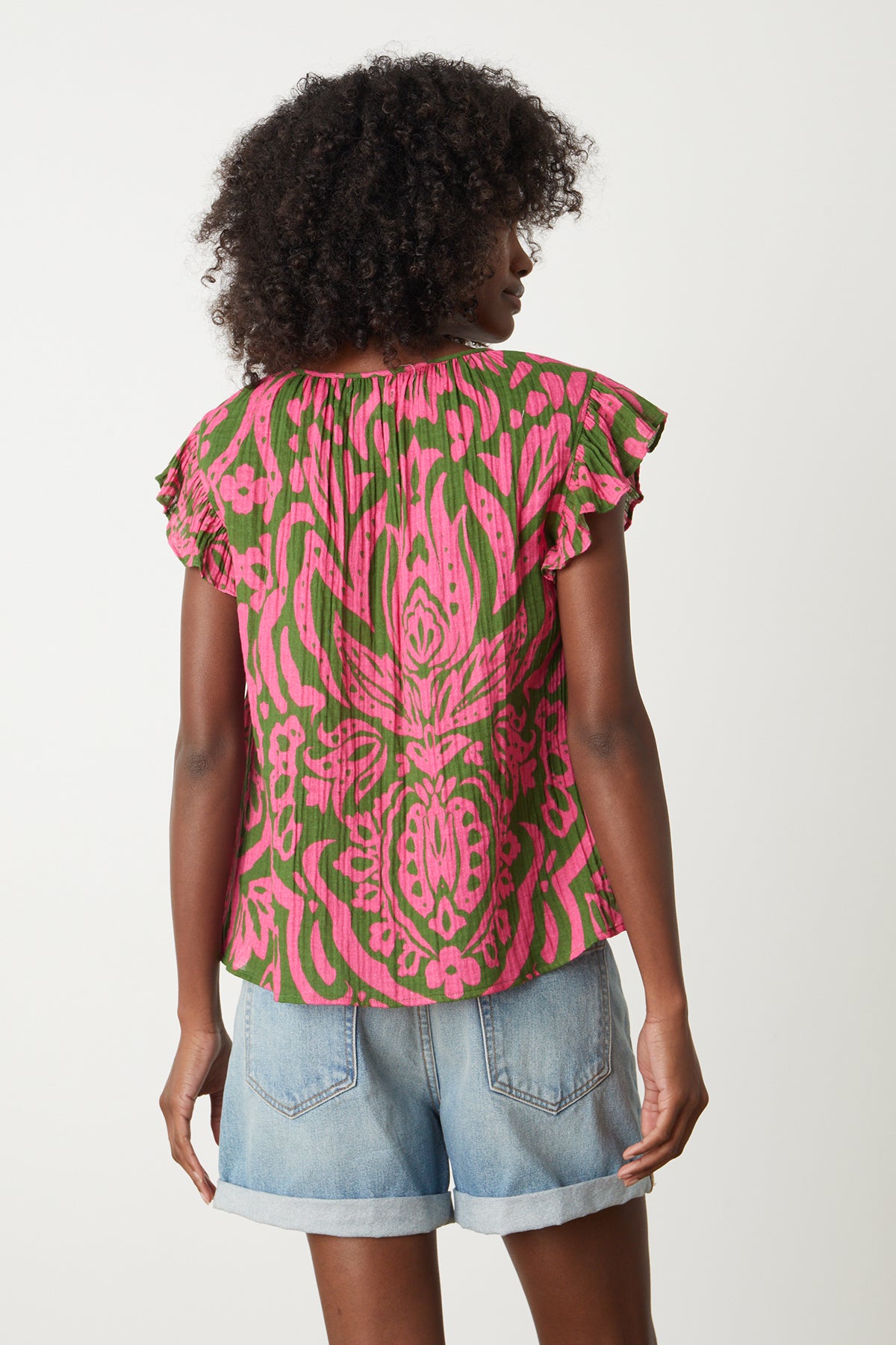   the back view of a woman wearing a Velvet by Graham & Spencer ALEAH PRINTED COTTON GAUZE TOP in pink and green. 