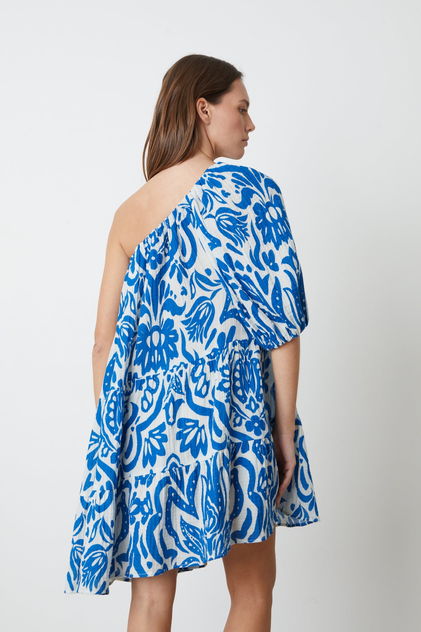 The back view of a woman wearing the Velvet by Graham & Spencer GRETCHEN PRINTED ONE SHOULDER DRESS.-26774928326849