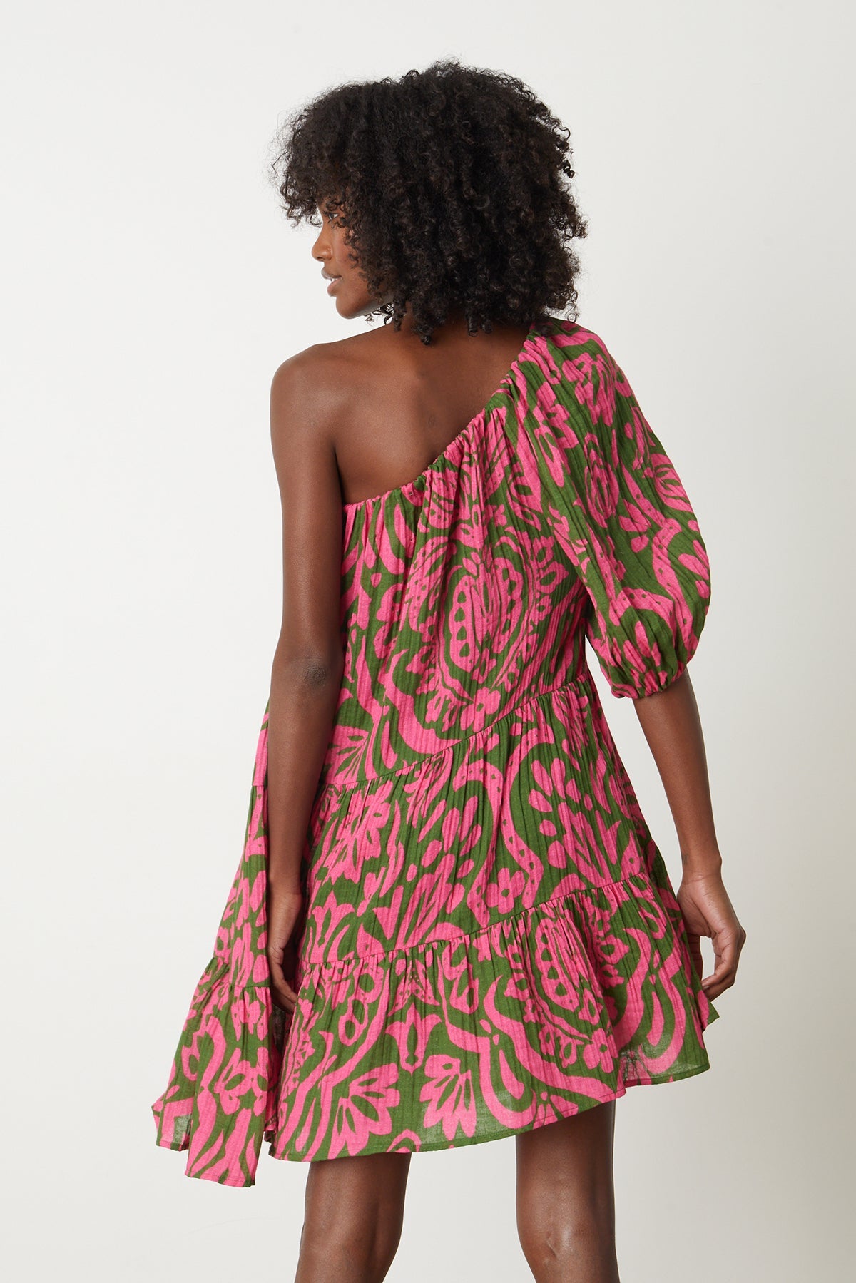 The back view of a woman wearing a Velvet by Graham & Spencer Gretchen Printed One Shoulder Dress in pink and green print.-26801042096321