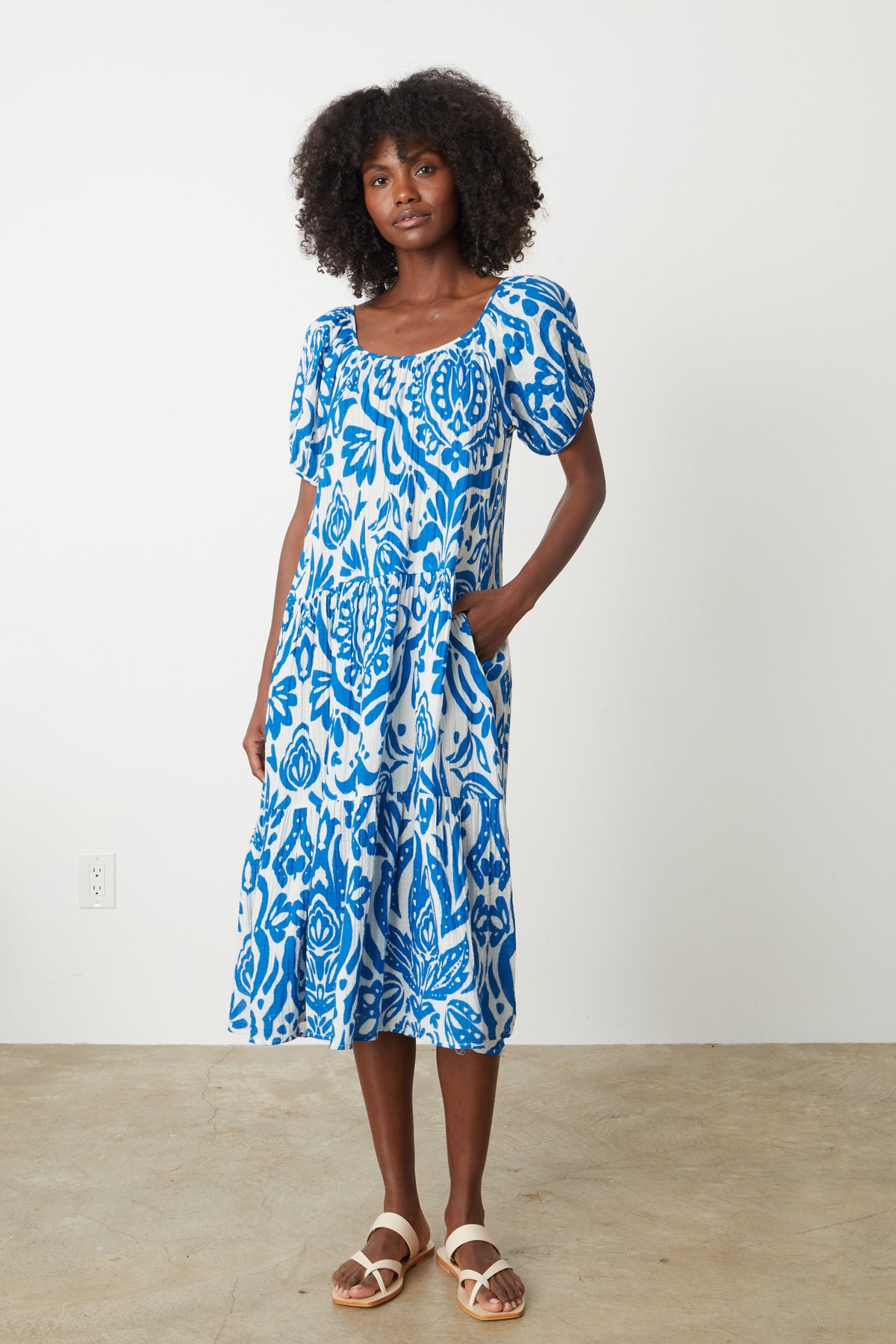   A woman wearing a blue and white floral MADILYN PRINTED COTTON GAUZE poufy sleeve MIDI DRESS by Velvet by Graham & Spencer. 